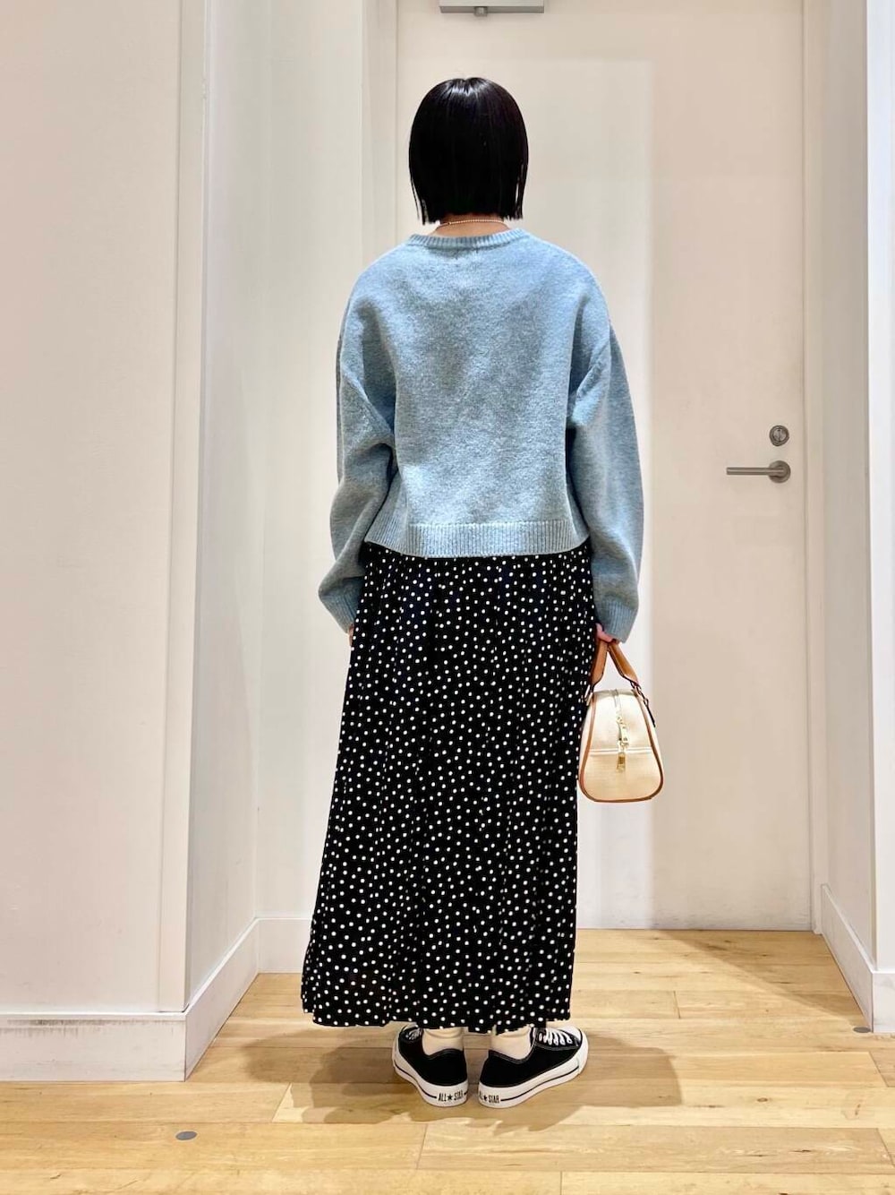 ブラック系のスニーカー、ブルー系のニット/セーター、イエロー系のボストンバッグを着用したレディースの冬コーディネートの6枚目の写真