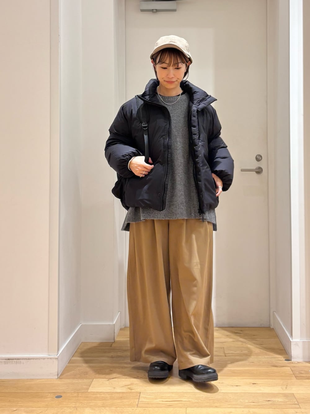 ベージュ系のその他パンツ、グレー系のニット/セーター、ブラック系のダウンジャケット/コートを着用したレディースの秋コーディネートの2枚目の写真