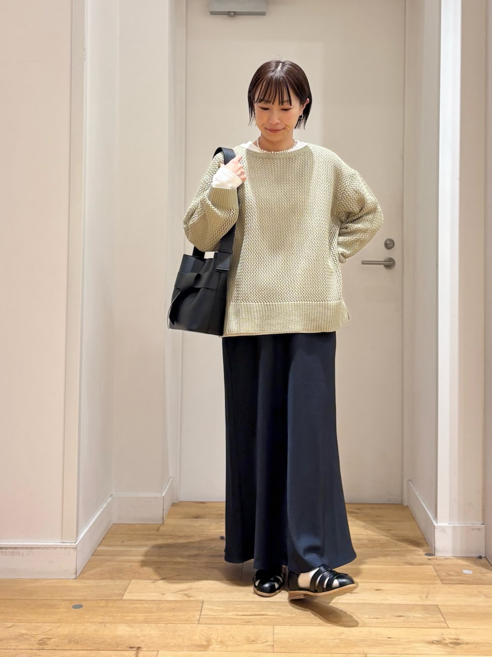 グリーン系のニット/セーター、ホワイト系のTシャツ/カットソー、ブルー系のスカートを着用したレディースの春コーディネートの4枚目の写真