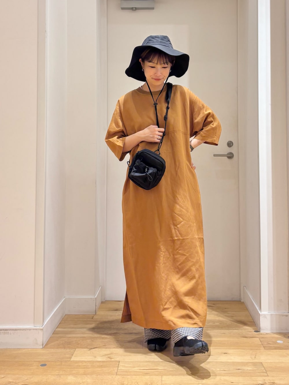 イエロー系のワンピース、ブラック系のショルダーバッグ、ブラック系のその他パンツを着用したレディースの夏コーディネートの2枚目の写真