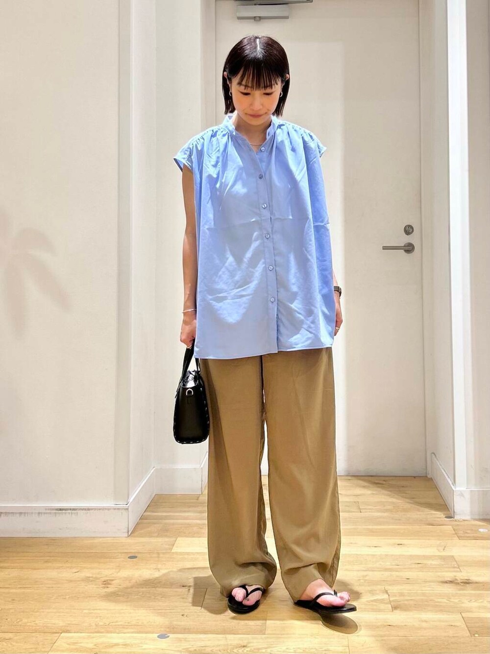 ブラック系のサンダル、ブラック系のショルダーバッグ、ブルー系のシャツ/ブラウスを着用したレディースの夏コーディネートの2枚目の写真