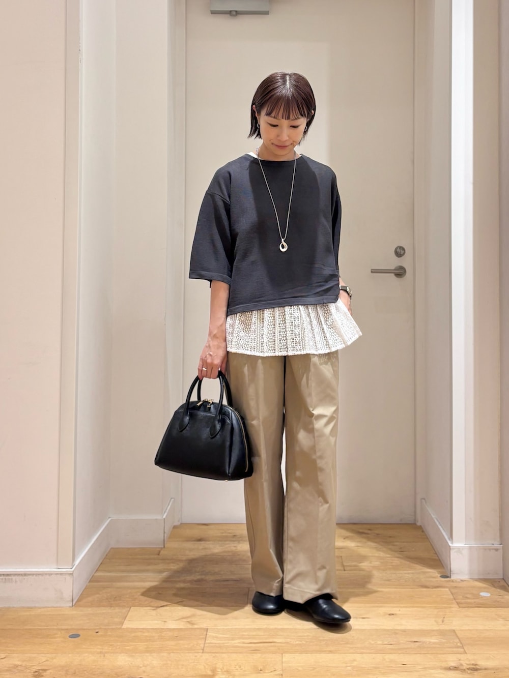 グレー系のニット/セーター、ベージュ系のその他パンツ、ブラック系のハンドバッグを着用したレディースの秋コーディネートの4枚目の写真