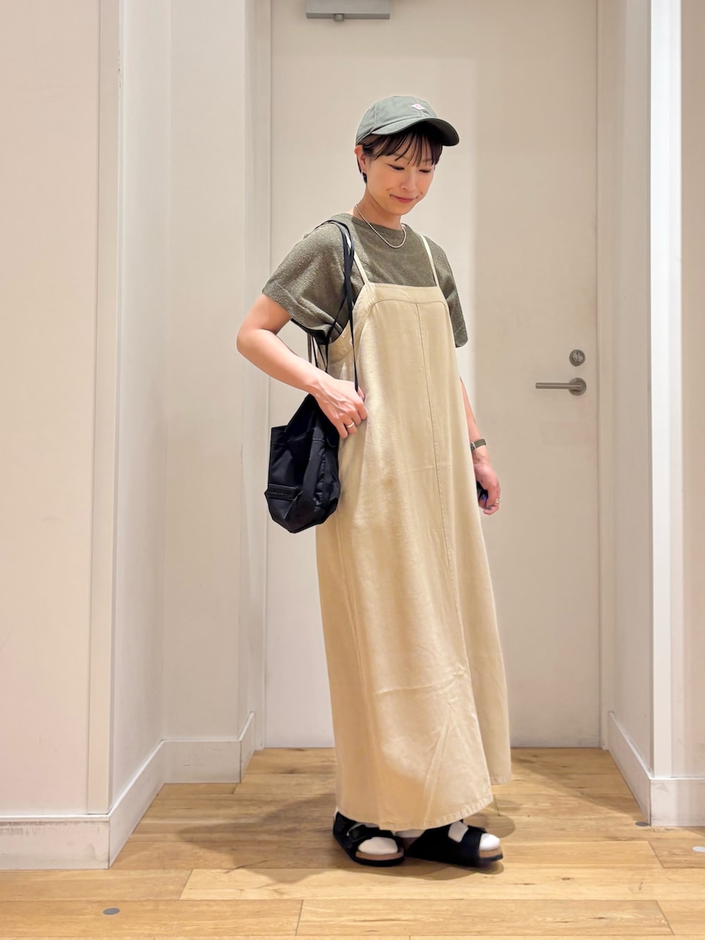 ベージュ系のワンピース、グリーン系のニット/セーター、ブラック系のサンダルを着用したレディースの夏コーディネートの5枚目の写真