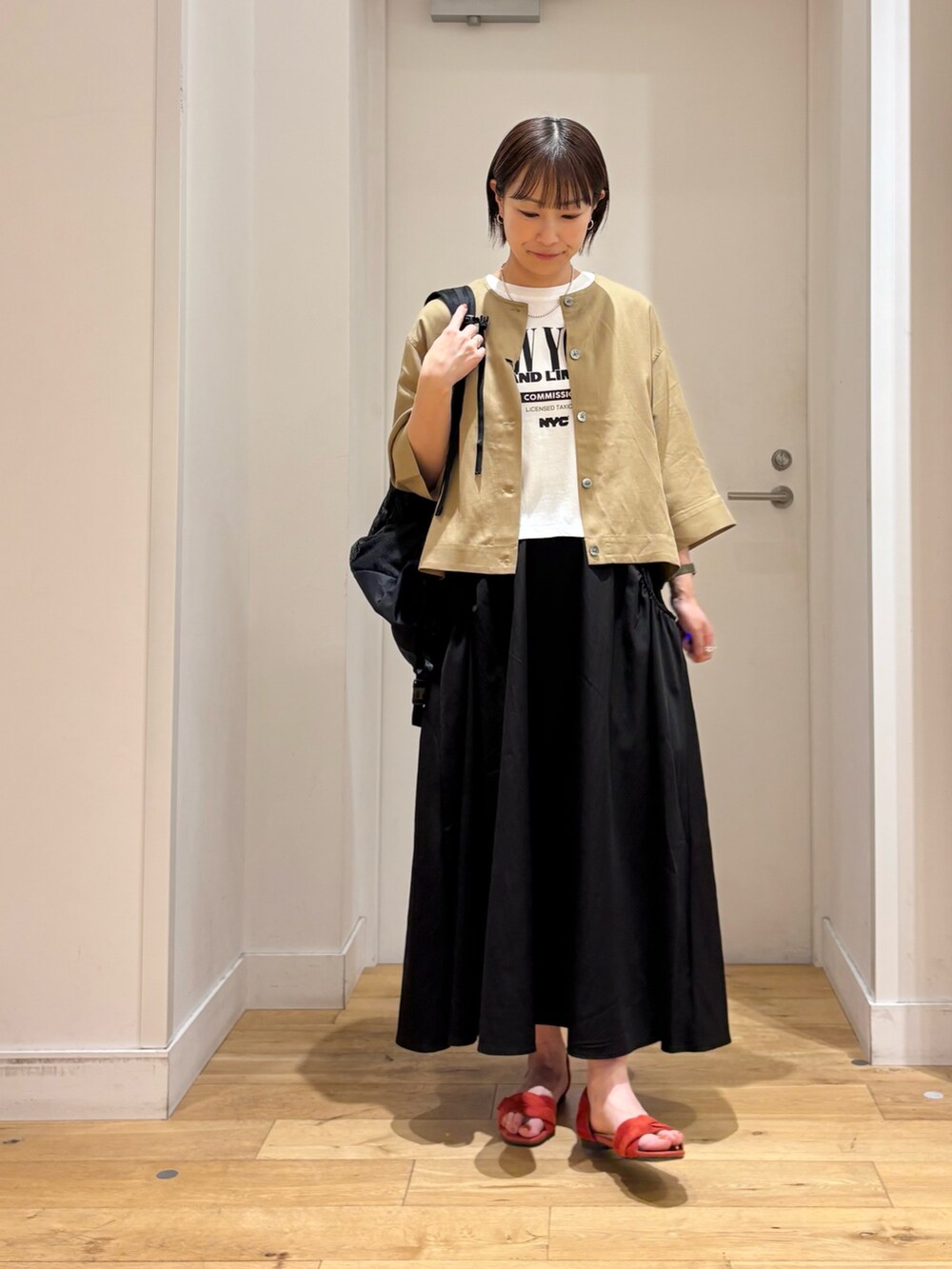 ベージュ系のシャツ/ブラウス、ブラック系のスカート、ホワイト系のTシャツ/カットソーを着用したレディースの春コーディネートの3枚目の写真