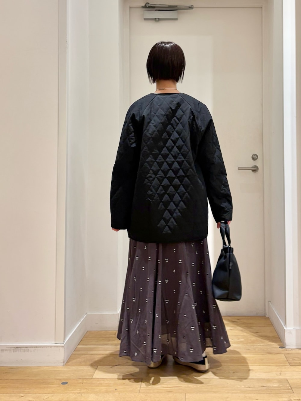 ブラック系のハンドバッグ、グレー系のニット/セーター、グレー系のスカートを着用したレディースの春コーディネートの6枚目の写真