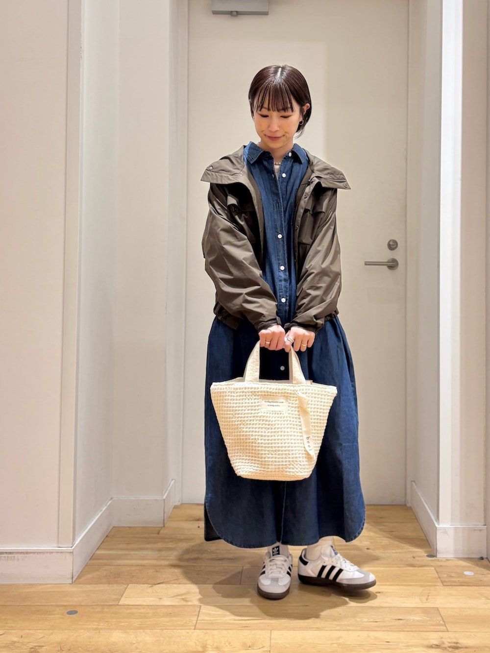 ブラウン系のナイロンジャケット、ブルー系のワンピース、ホワイト系のスニーカーを着用したレディースの春コーディネートの5枚目の写真