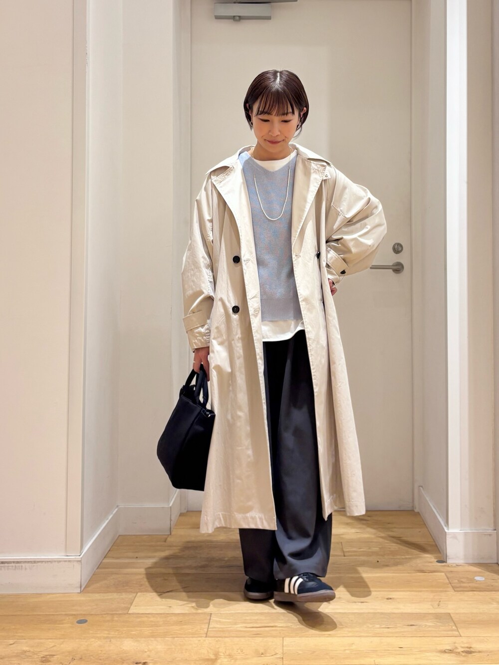 ブルー系のニット/セーター、ホワイト系のTシャツ/カットソー、ベージュ系のトレンチコートを着用したレディースの春コーディネートの2枚目の写真