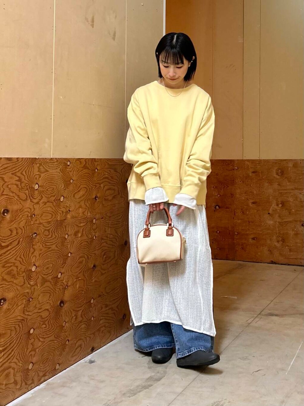 イエロー系のボストンバッグ、イエロー系のスウェット、ホワイト系のワンピースを着用したレディースの春コーディネートの2枚目の写真