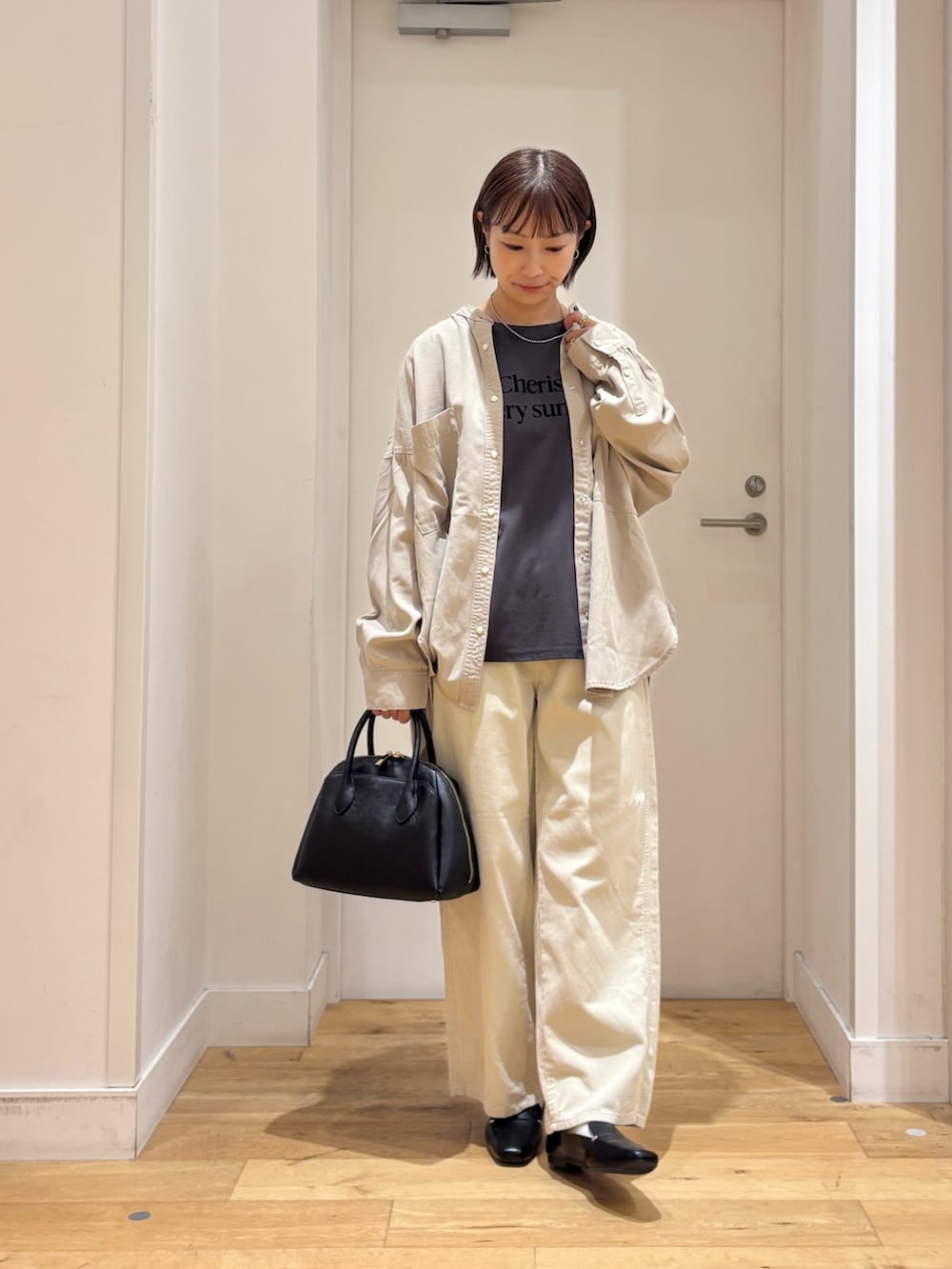 グレー系のTシャツ/カットソー、ホワイト系のその他パンツ、ブラック系のハンドバッグを着用したレディースの秋コーディネートの3枚目の写真