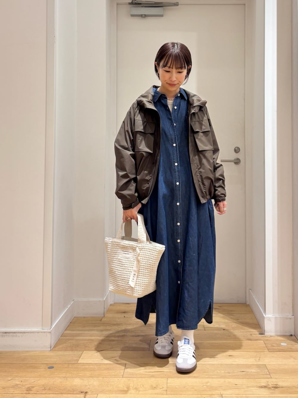 ブラウン系のナイロンジャケット、ブルー系のワンピース、ホワイト系のスニーカーを着用したレディースの春コーディネートの3枚目の写真