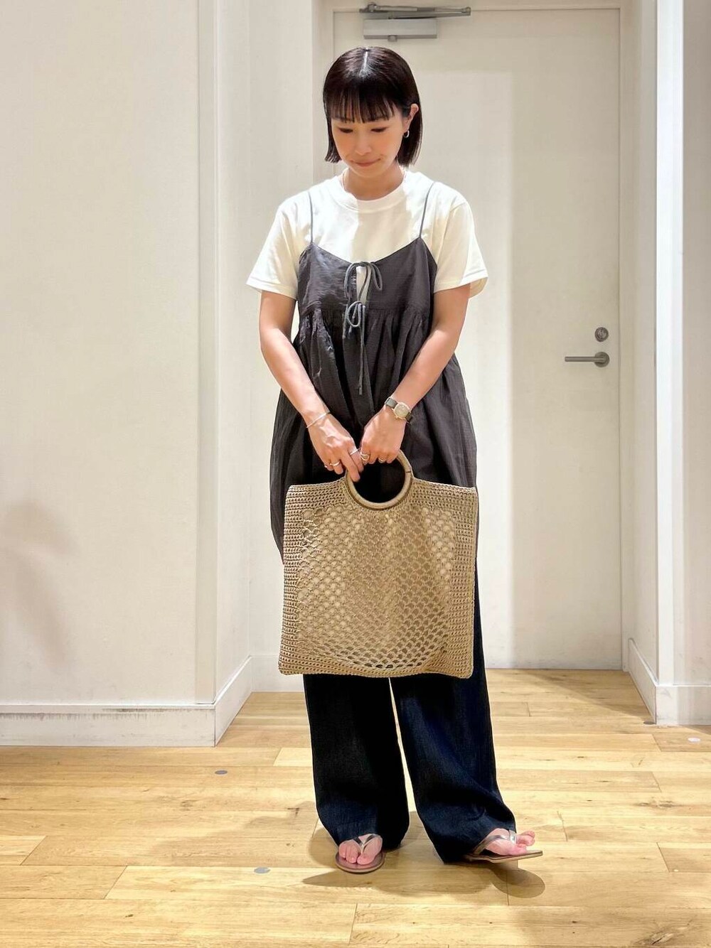 ブルー系のデニムパンツ、ホワイト系のTシャツ/カットソー、シルバー系のサンダルを着用したレディースの夏コーディネートの2枚目の写真