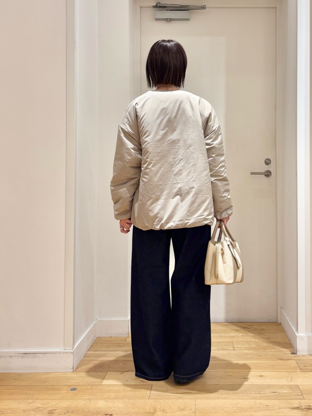 ベージュ系のブルゾン、ベージュ系のニット/セーター、ホワイト系のハンドバッグを着用したレディースの冬コーディネートの5枚目の写真