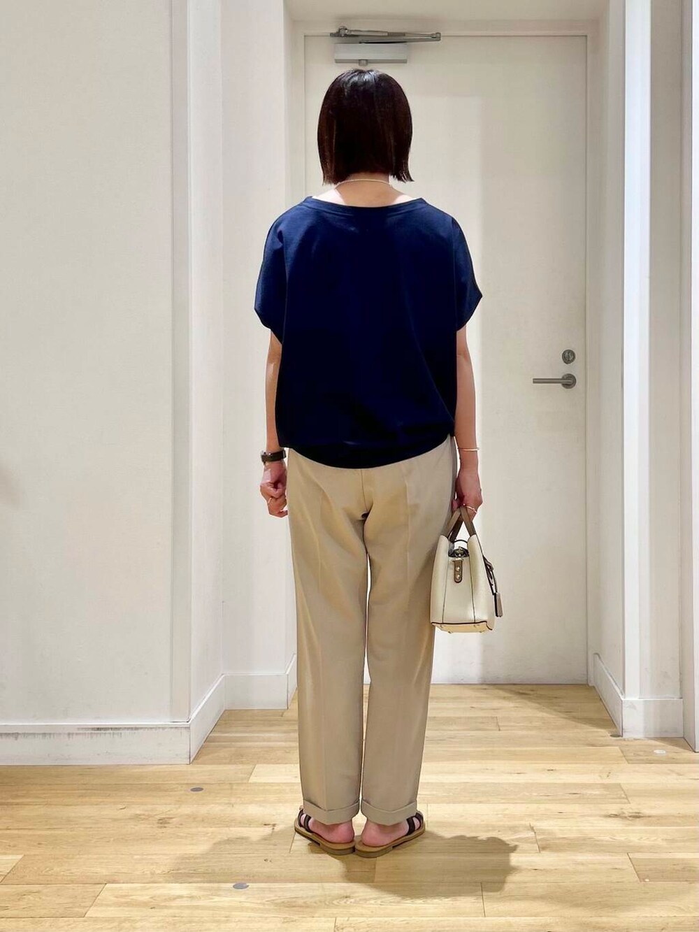 ホワイト系のハンドバッグ、ベージュ系のその他パンツ、ブラック系のサンダルを着用したレディースの夏コーディネートの6枚目の写真