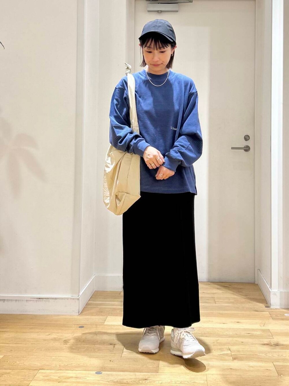 グレー系のショルダーバッグ、ブラック系のスカート、グレー系のスニーカーを着用したレディースの夏コーディネートの2枚目の写真