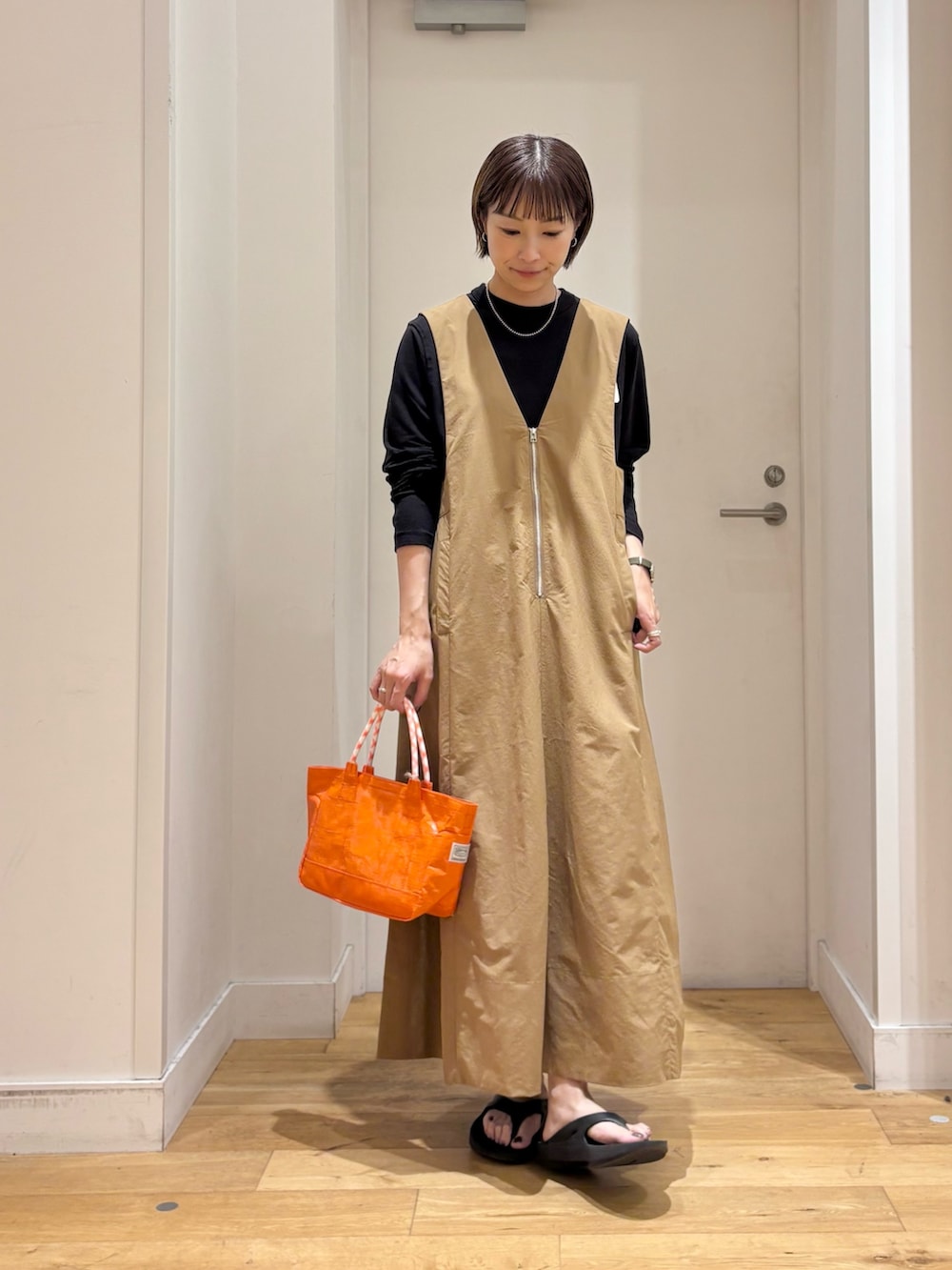ブラック系のTシャツ/カットソー、ベージュ系のワンピース、オレンジ系のショルダーバッグを着用したレディースの夏コーディネートの2枚目の写真