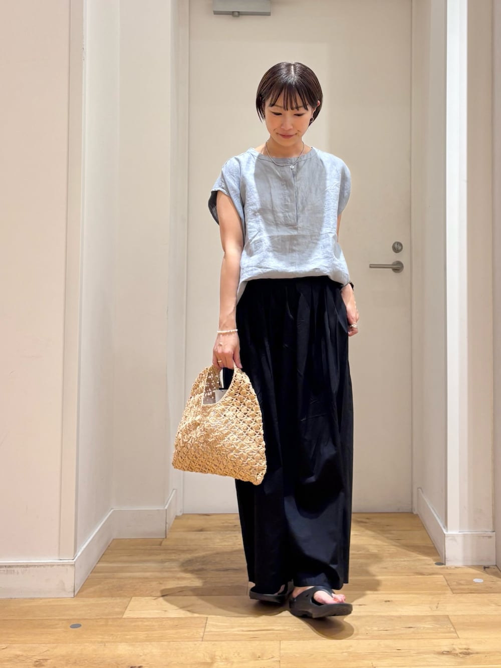 ブルー系のシャツ/ブラウス、ブラック系のその他パンツ、ベージュ系のハンドバッグを着用したレディースの夏コーディネートの4枚目の写真