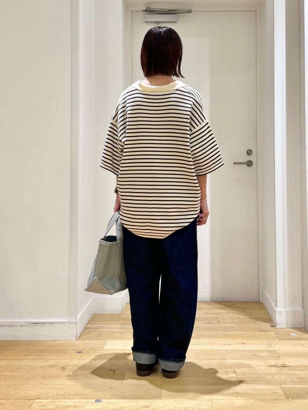 ホワイト系のニット/セーター、ブラック系のスニーカー、ブルー系のデニムパンツを着用したレディースの夏コーディネートの5枚目の写真