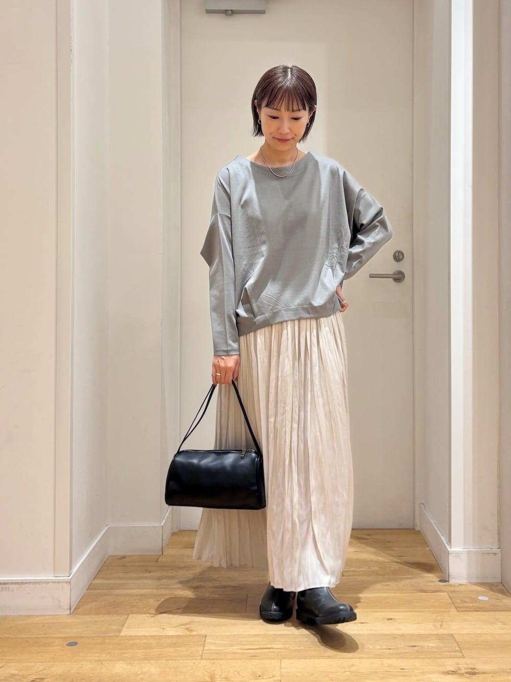 ブルー系のTシャツ/カットソー、ブラック系のハンドバッグ、ブラック系のレインシューズを着用したレディースの秋コーディネートの3枚目の写真