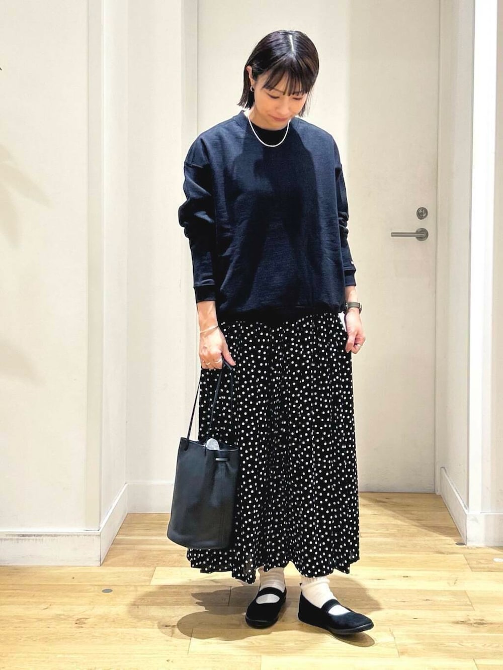 ブラック系のスニーカー、ブラック系のショルダーバッグ、ブラック系のスカートを着用したレディースの秋コーディネートの3枚目の写真