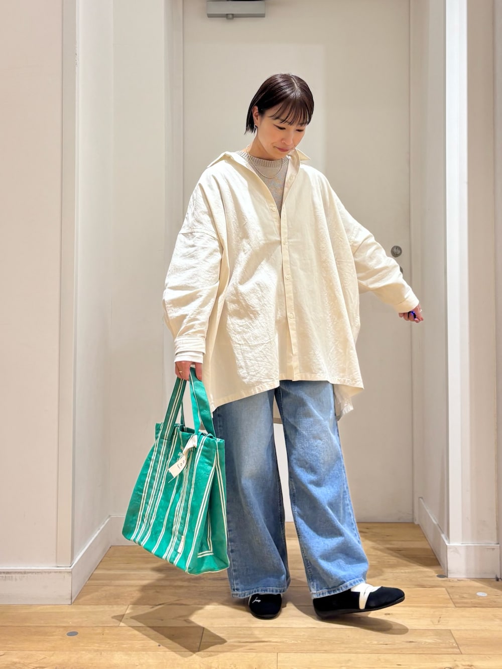 グレー系のニット/セーター、ブルー系のデニムパンツ、ブラック系のスニーカーを着用したレディースの春コーディネートの4枚目の写真