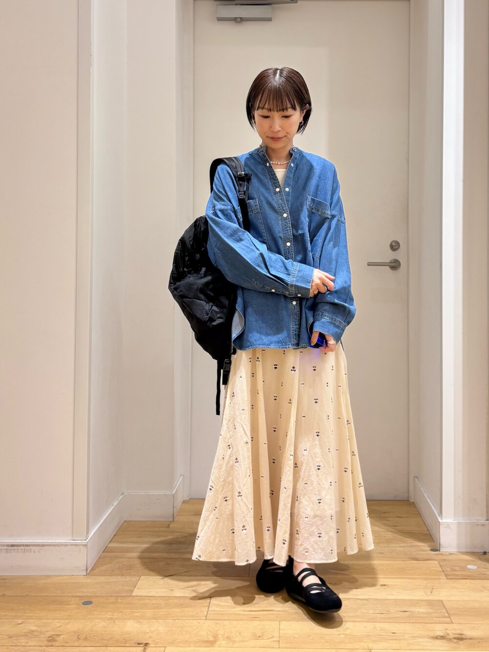 ブルー系のシャツ/ブラウス、ホワイト系のスカート、ブラック系のバックパック/リュックを着用したレディースの春コーディネートの2枚目の写真