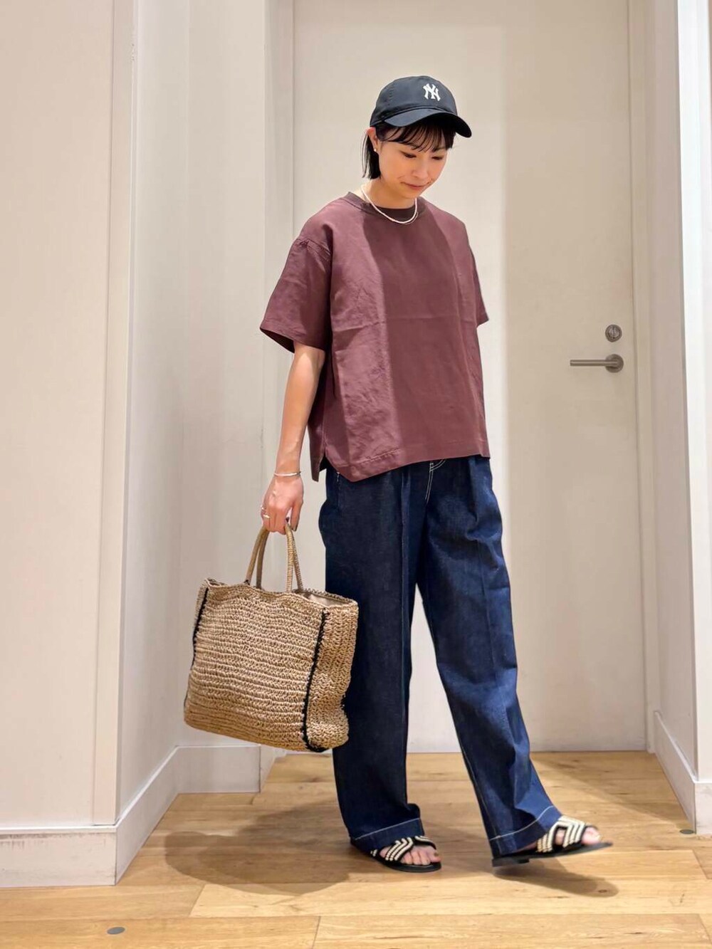 ベージュ系のトートバッグ、ブルー系のデニムパンツ、ブラック系のサンダルを着用したレディースの夏コーディネートの5枚目の写真