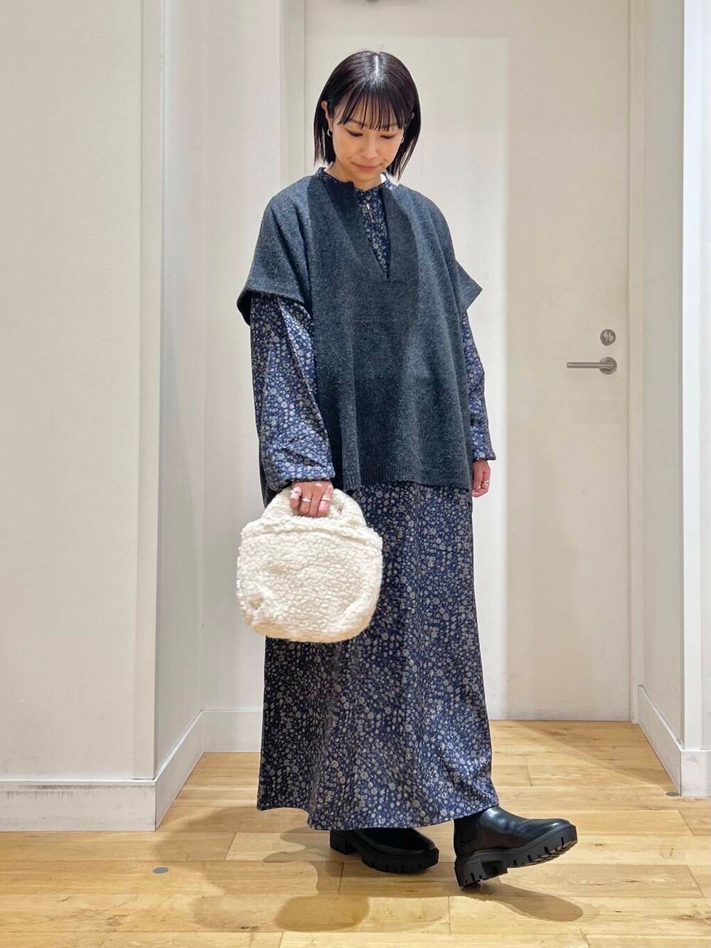 ブラック系のブーツ、ベージュ系のハンドバッグ、ブルー系のワンピースを着用したレディースの冬コーディネートの4枚目の写真