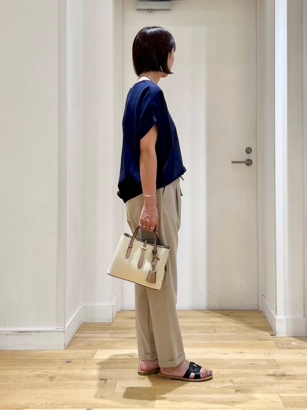ホワイト系のハンドバッグ、ベージュ系のその他パンツ、ブラック系のサンダルを着用したレディースの夏コーディネートの5枚目の写真