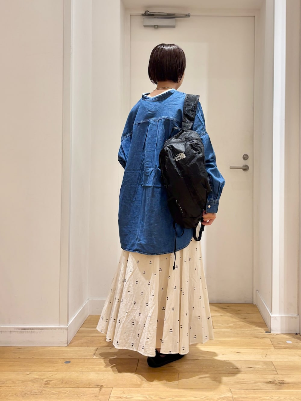 ブルー系のシャツ/ブラウス、ホワイト系のスカート、ブラック系のバックパック/リュックを着用したレディースの春コーディネートの6枚目の写真