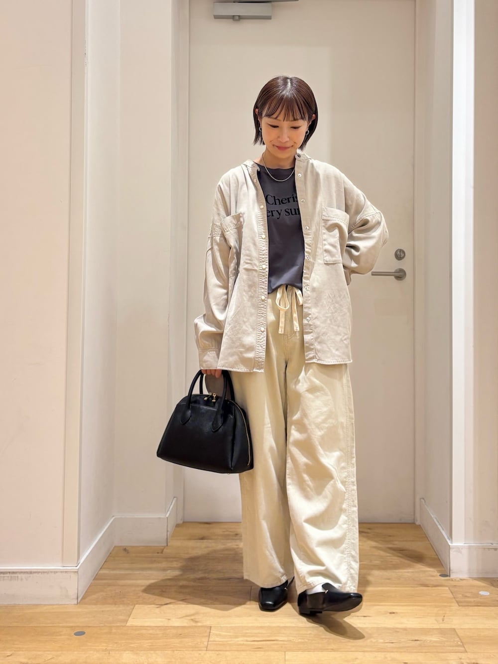 グレー系のTシャツ/カットソー、ホワイト系のその他パンツ、ブラック系のハンドバッグを着用したレディースの秋コーディネートの2枚目の写真