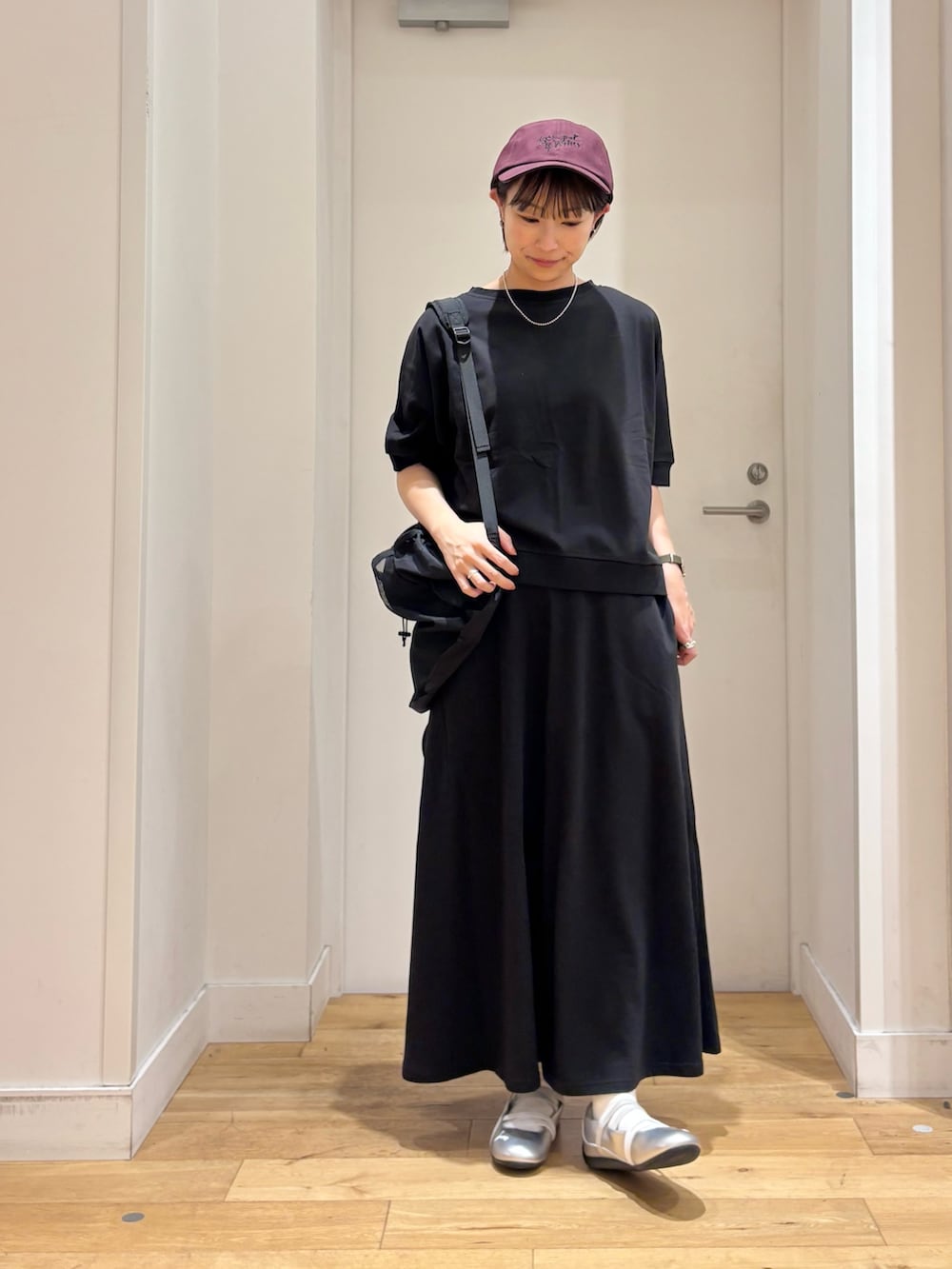 ブラック系のTシャツ/カットソー、ブラック系のバックパック/リュック、シルバー系のスニーカーを着用したレディースの春コーディネートの2枚目の写真