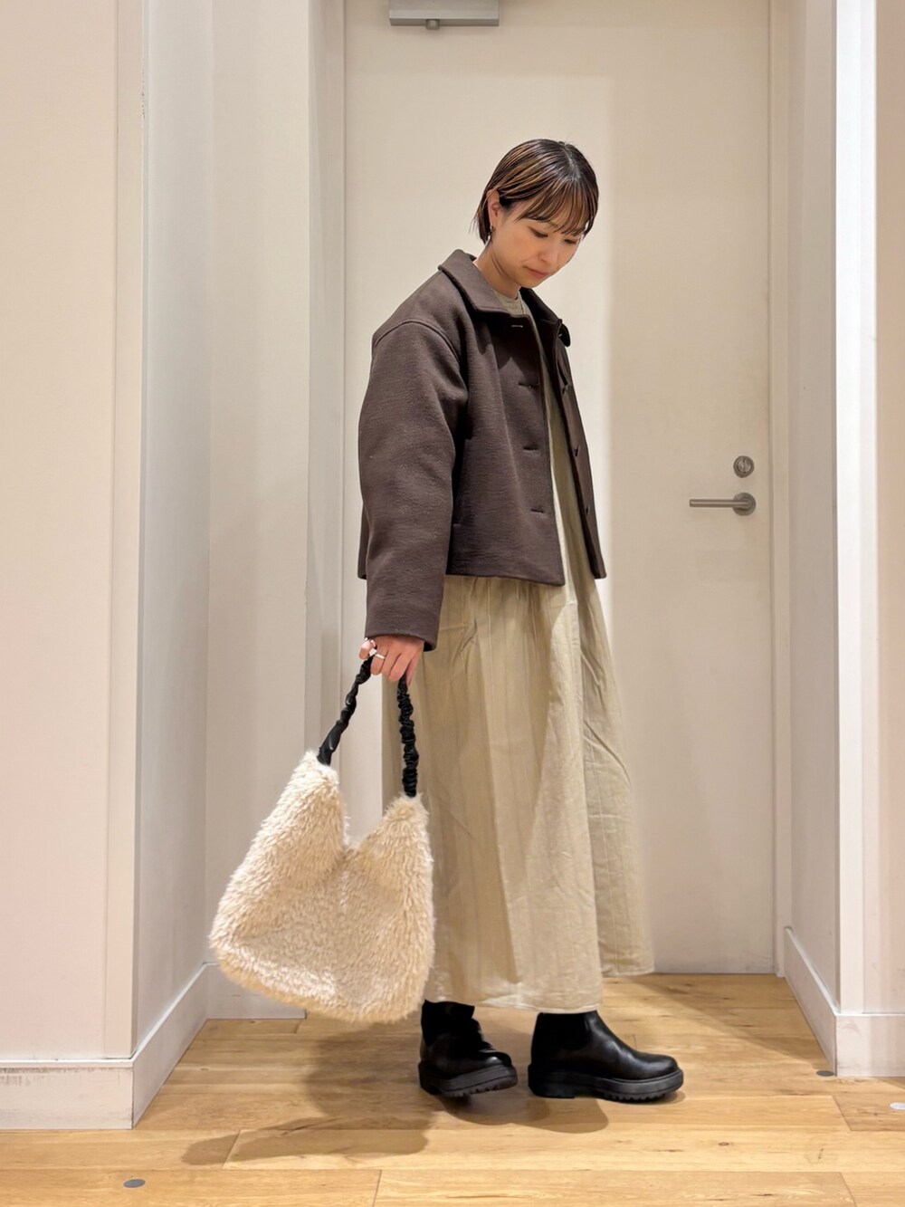 ブラウン系のその他アウター、ベージュ系のワンピース、ブラック系のブーツを着用したレディースの秋コーディネートの4枚目の写真