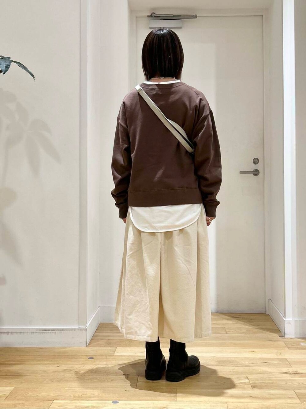 ブラウン系のスウェット、ホワイト系のスカート、ベージュ系のショルダーバッグを着用したレディースの秋コーディネートの5枚目の写真