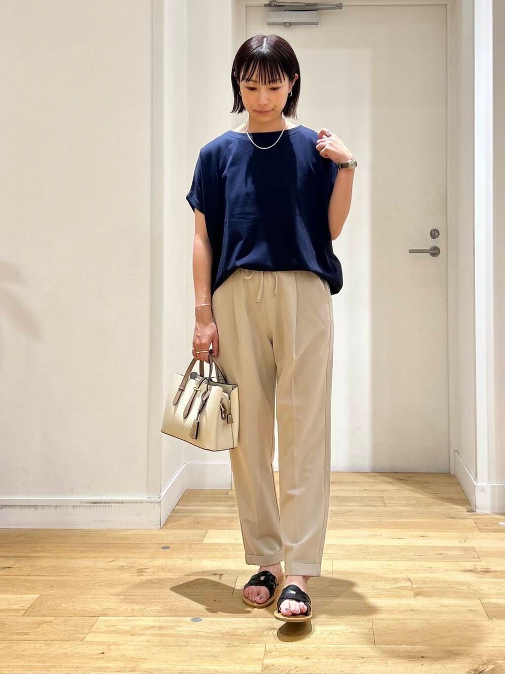 ホワイト系のハンドバッグ、ベージュ系のその他パンツ、ブラック系のサンダルを着用したレディースの夏コーディネートの2枚目の写真