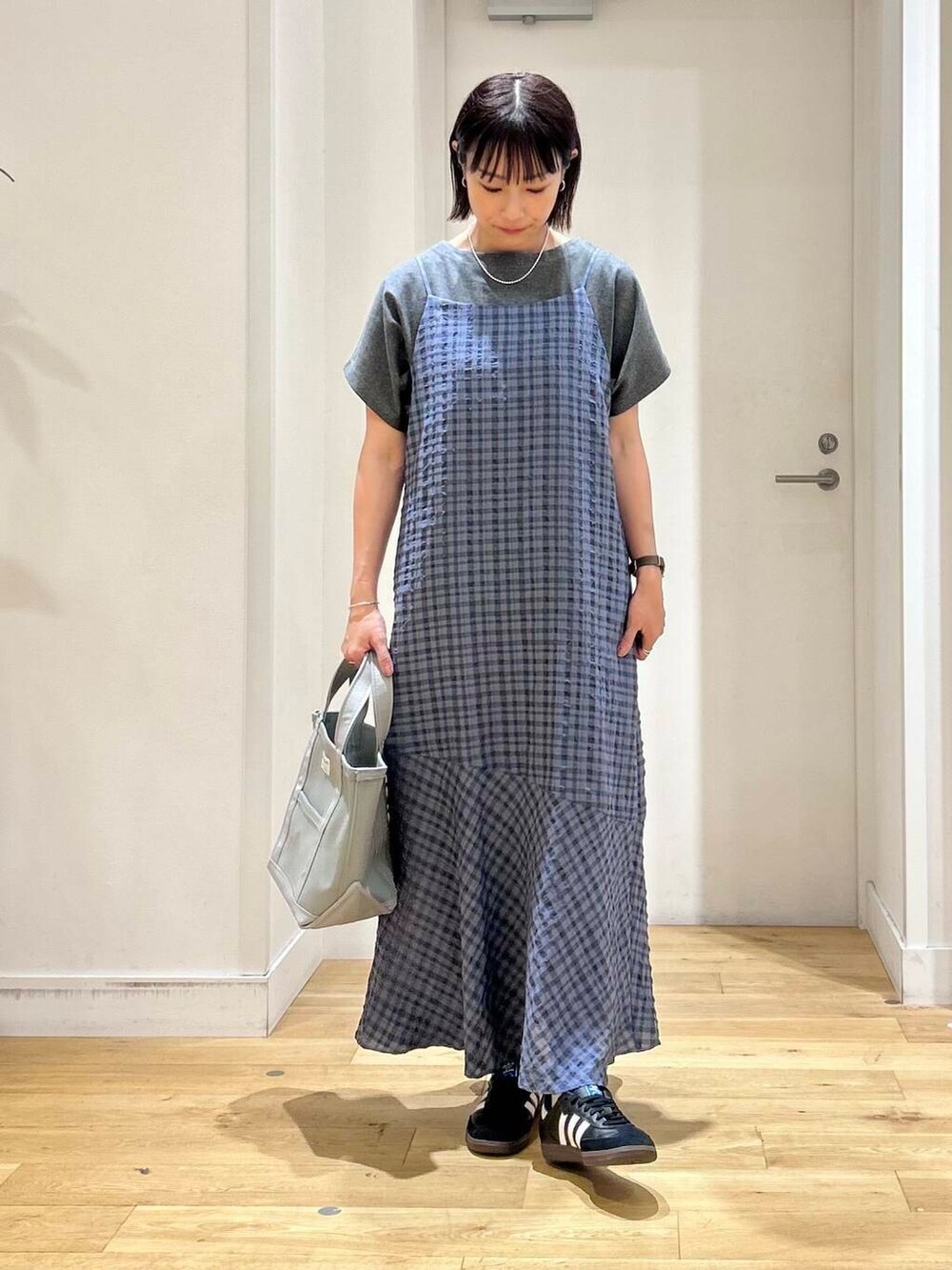 グレー系のTシャツ/カットソー、ブルー系のワンピース、ブラック系のスニーカーを着用したレディースの夏コーディネートの2枚目の写真