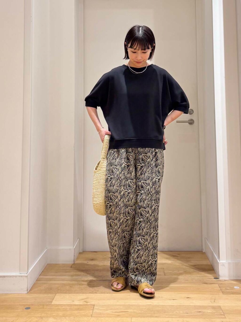 ベージュ系のトートバッグ、イエロー系のサンダル、グレー系のその他パンツを着用したレディースの夏コーディネートの2枚目の写真