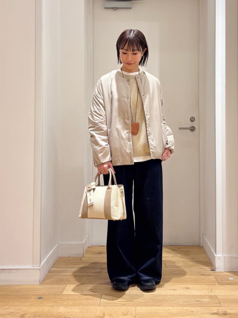 ベージュ系のブルゾン、ベージュ系のニット/セーター、ホワイト系のハンドバッグを着用したレディースの冬コーディネートの3枚目の写真