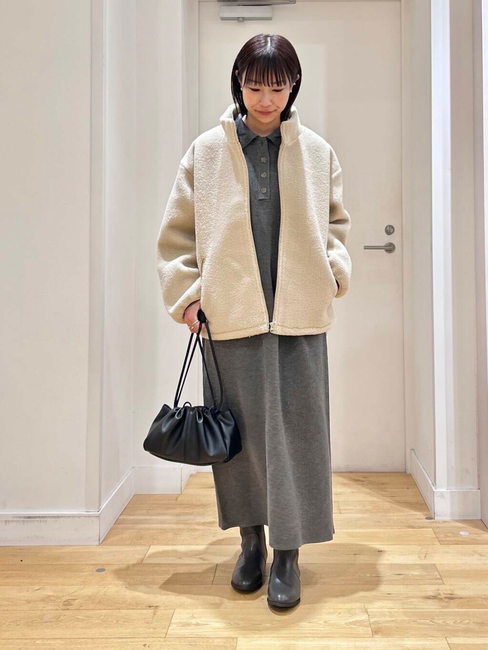 グレー系のブーツ、ホワイト系のブルゾン、グレー系のワンピースを着用したレディースの冬コーディネートの3枚目の写真