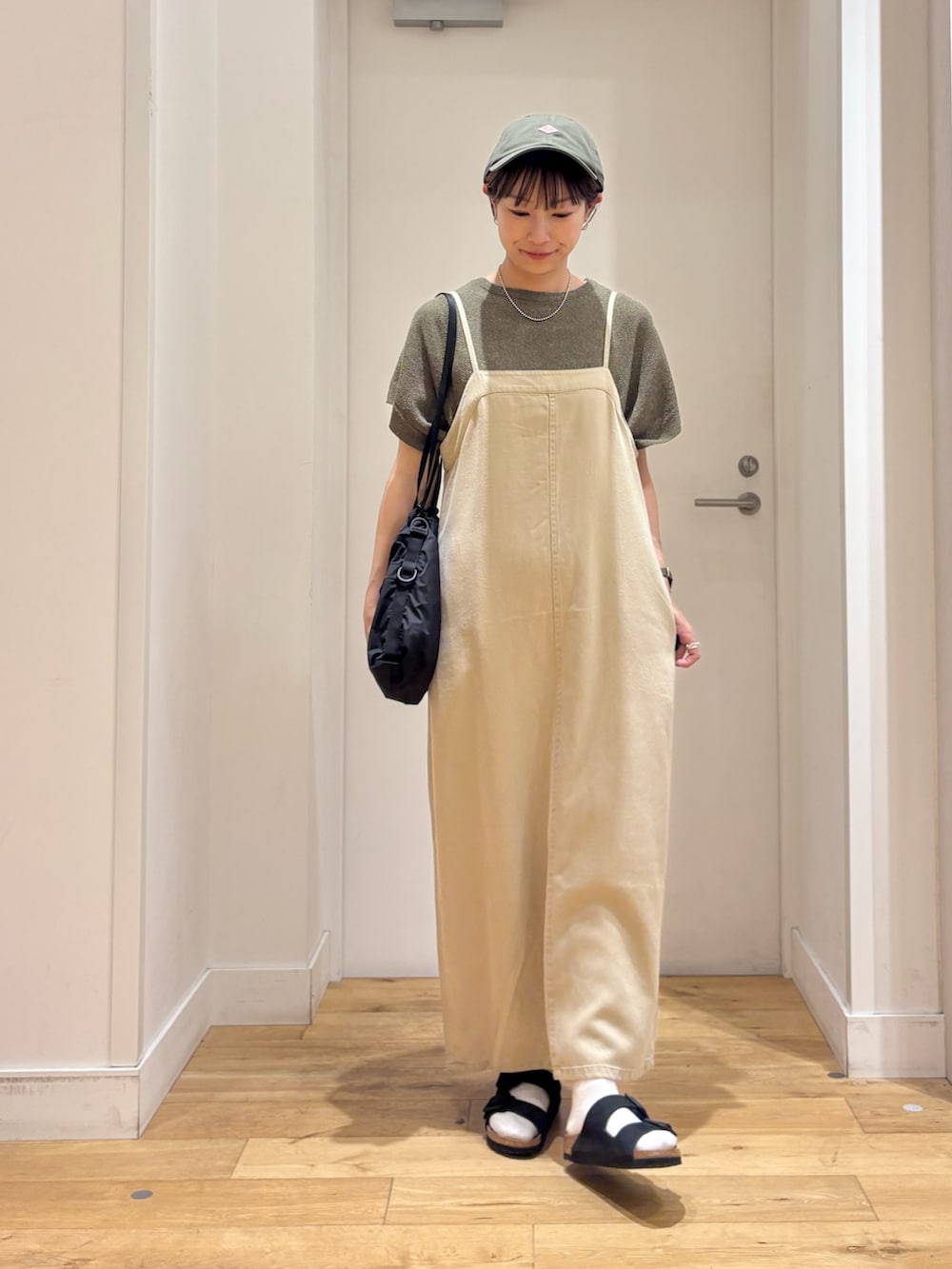 ベージュ系のワンピース、グリーン系のニット/セーター、ブラック系のサンダルを着用したレディースの夏コーディネートの3枚目の写真