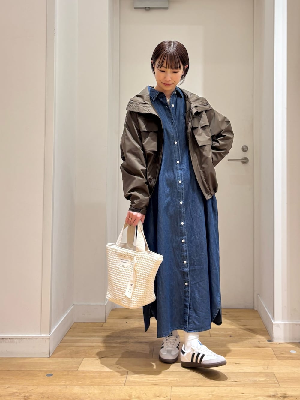 ブラウン系のナイロンジャケット、ブルー系のワンピース、ホワイト系のスニーカーを着用したレディースの春コーディネートの4枚目の写真