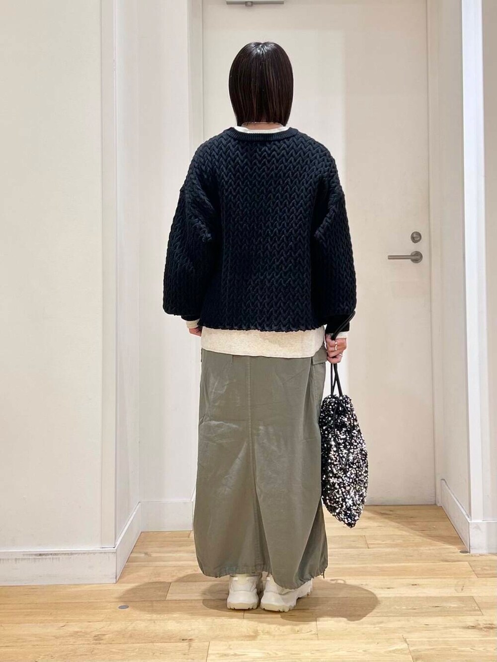 グリーン系のスカート、ホワイト系のスニーカー、シルバー系のトートバッグを着用したレディースの冬コーディネートの5枚目の写真