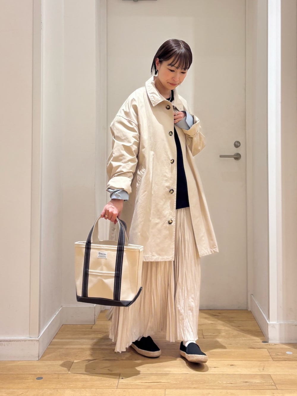 ホワイト系のTシャツ/カットソー、ベージュ系のステンカラーコート、ブルー系のベストを着用したレディースの春コーディネートの5枚目の写真