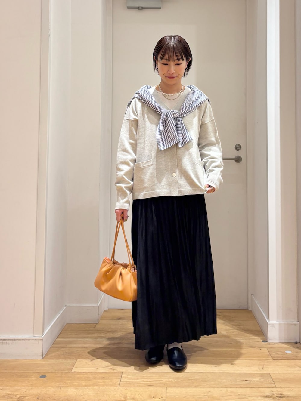 ベージュ系のTシャツ/カットソー、ベージュ系のカーディガン/ボレロ、ブラック系のスカートを着用したレディースの春コーディネートの3枚目の写真