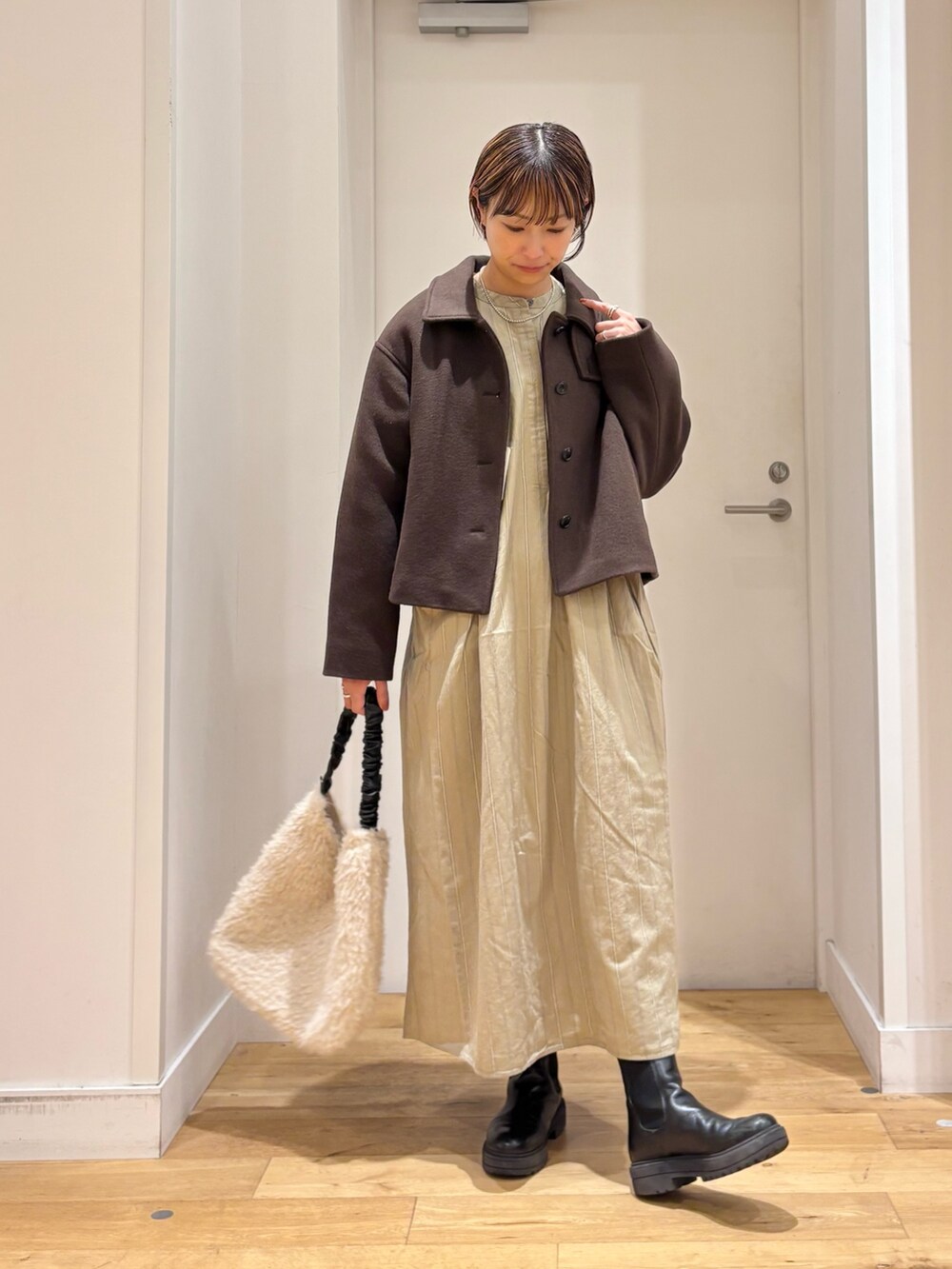 ブラウン系のその他アウター、ベージュ系のワンピース、ブラック系のブーツを着用したレディースの秋コーディネートの3枚目の写真