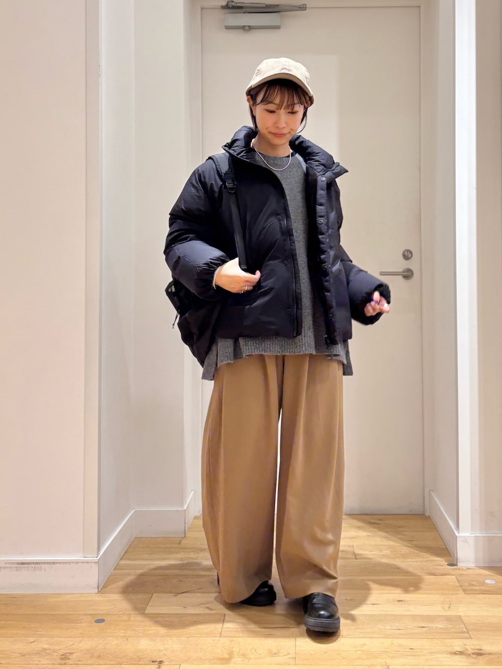 ベージュ系のその他パンツ、グレー系のニット/セーター、ブラック系のダウンジャケット/コートを着用したレディースの秋コーディネートの3枚目の写真