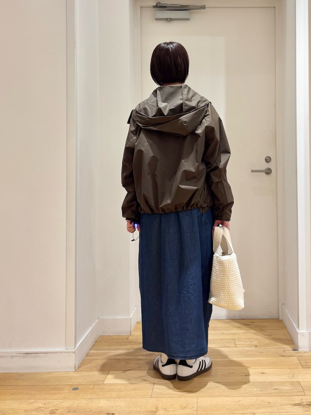 ブラウン系のナイロンジャケット、ブルー系のワンピース、ホワイト系のスニーカーを着用したレディースの春コーディネートの7枚目の写真