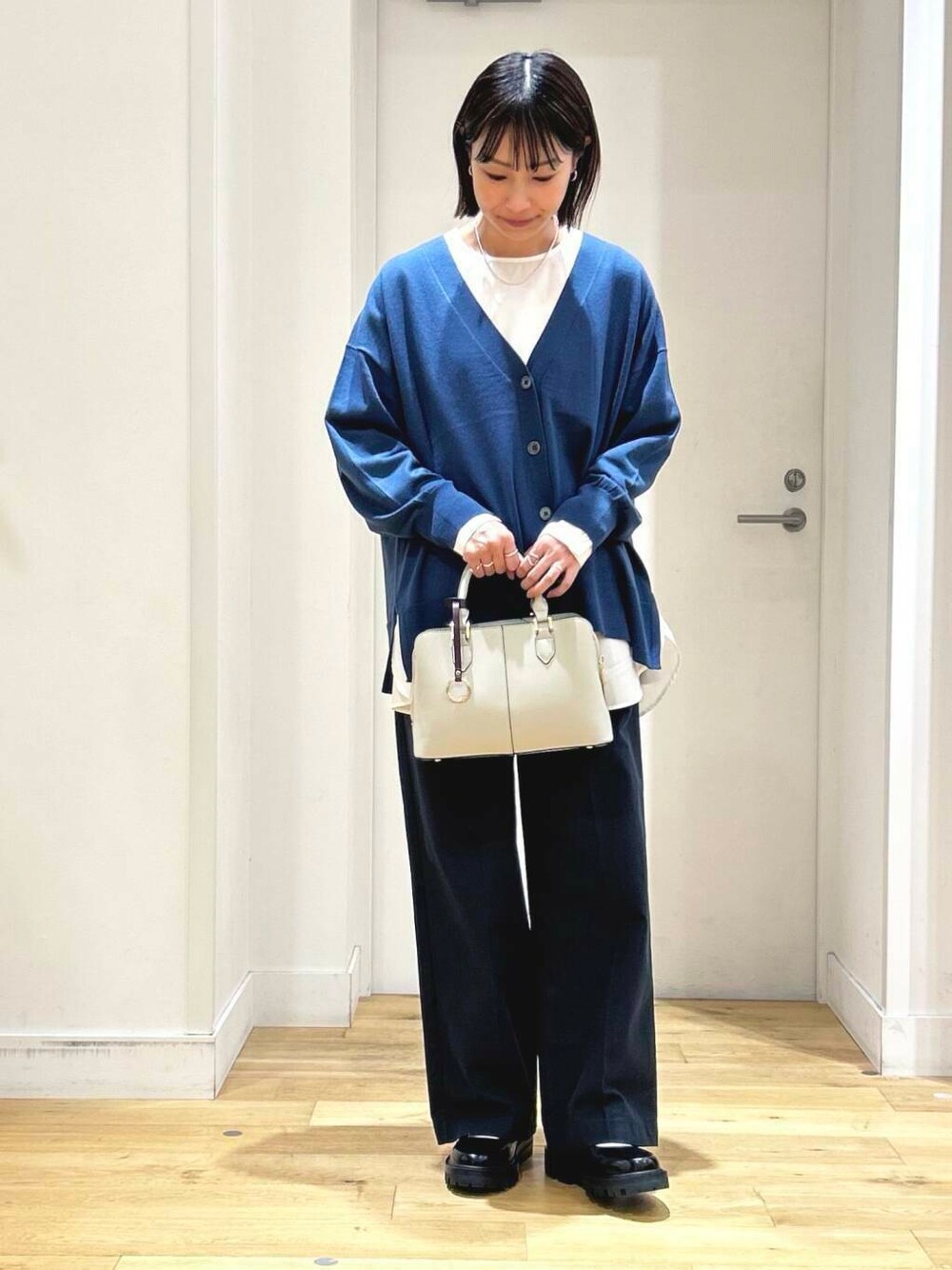 ブルー系のカーディガン/ボレロ、ホワイト系のシャツ/ブラウス、グレー系のハンドバッグを着用したレディースの秋コーディネートの2枚目の写真