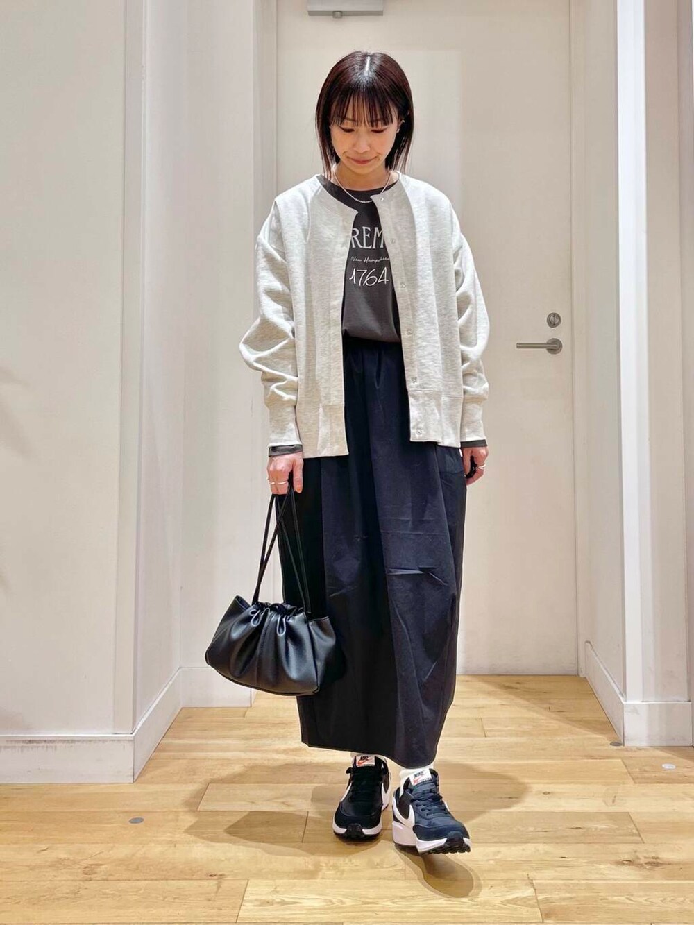 グレー系のTシャツ/カットソー、ブラック系のショルダーバッグ、ベージュ系のカーディガン/ボレロを着用したレディースの冬コーディネートの2枚目の写真