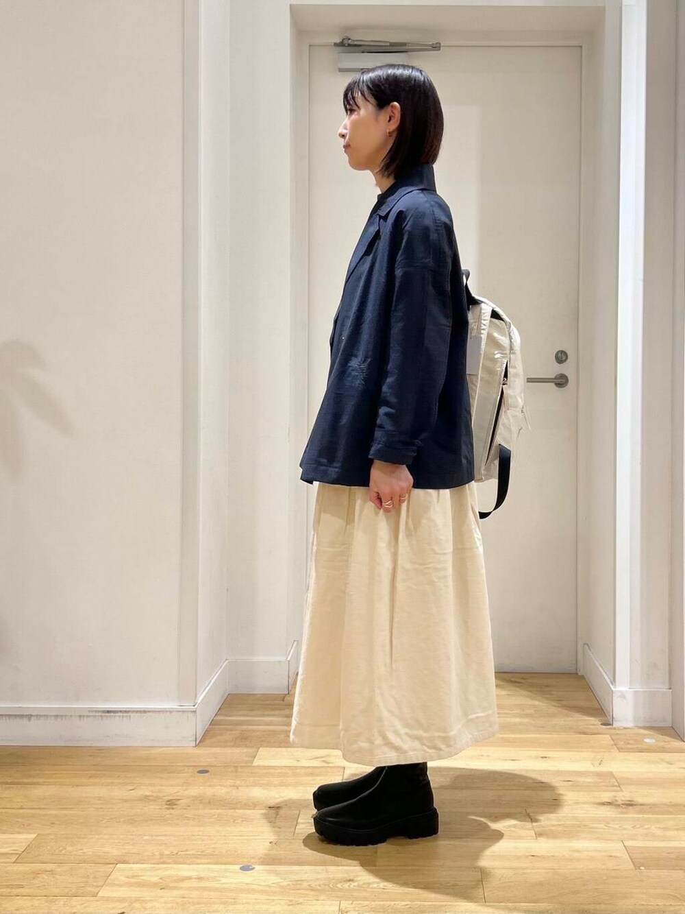 ホワイト系のバックパック/リュック、ホワイト系のTシャツ/カットソー、ブラック系のブーツを着用したレディースの秋コーディネートの4枚目の写真