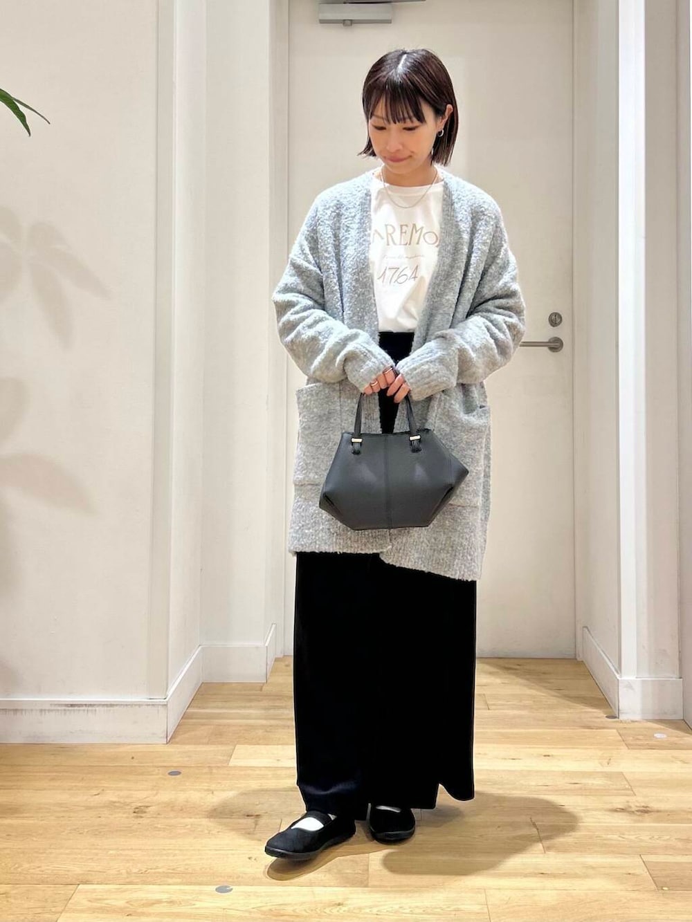 ブラック系のスニーカー、ブラック系のショルダーバッグ、ブラック系のワンピースを着用したレディースの秋コーディネートの3枚目の写真